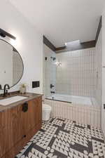 Full bathroom featuring tiled shower / bath combo, vanity, and toilet