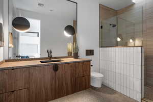 Bathroom with a tile shower, vanity, and toilet