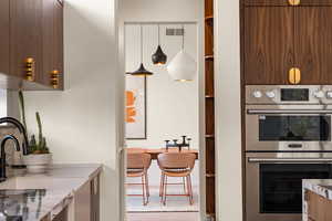 Kitchen featuring hanging light fixtures, sink, and stainless steel double oven