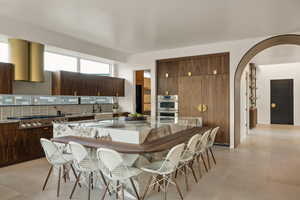 Kitchen with a breakfast bar, appliances with stainless steel finishes, tasteful backsplash, light stone counters, and a kitchen island