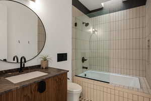 Full bathroom featuring vanity, tiled shower / bath combo, and toilet