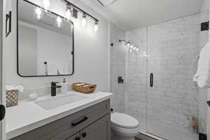 Bathroom with vanity, an enclosed shower, and toilet