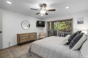 Bedroom with hardwood / wood-style floors, access to exterior, and ceiling fan