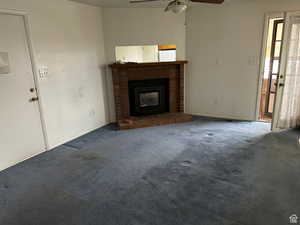 Unfurnished living room featuring a fireplace, carpet floors, and ceiling fan