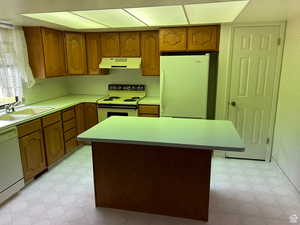 Kitchen with white appliances, a center island, and sink