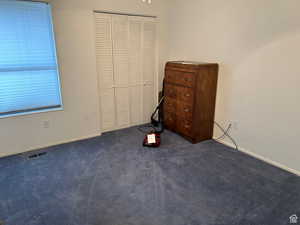 Unfurnished bedroom featuring a closet and dark colored carpet