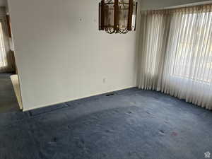 Unfurnished room with a chandelier and dark carpet