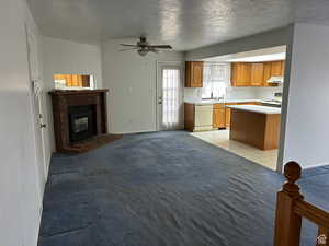 Kitchen featuring a fireplace, sink, light colored carpet, white appliances, and a textured ceiling