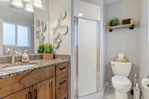 Bathroom featuring vanity, tile patterned floors, a shower with door, and toilet