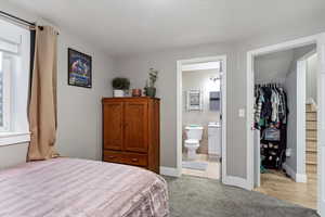 Bedroom featuring a walk in closet, connected bathroom, light colored carpet, and a closet