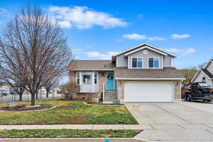 Tri-level home featuring a garage and a front lawn