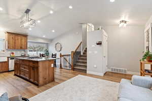 Kitchen featuring pendant lighting, stainless steel appliances, a kitchen island, and light wood-type flooring