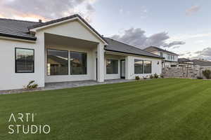 Back house at dusk with a yard and a patio