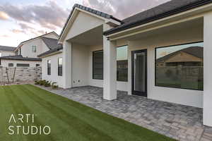 Back house at dusk with a yard and a patio area