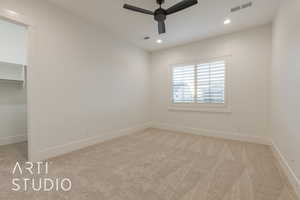 Unfurnished bedroom with ceiling fan, a wall unit AC, a spacious closet, light colored carpet, and a closet