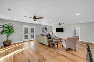 Living room with french doors, ceiling fan, and light hardwood / wood-style flooring