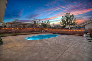 Pool at dusk featuring a patio