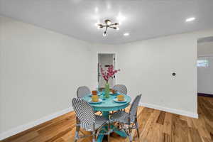 Dining space featuring an inviting chandelier, wood-type flooring, and a textured ceiling