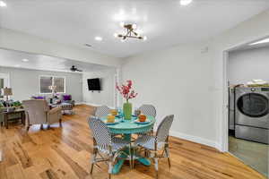 Dining space with washer / clothes dryer, ceiling fan with notable chandelier, a textured ceiling, and light wood-type flooring