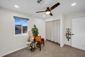 Sitting room featuring light colored carpet and ceiling fan