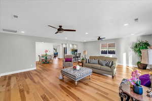 Living room featuring ceiling fan, a textured ceiling, and light hardwood / wood-style flooring