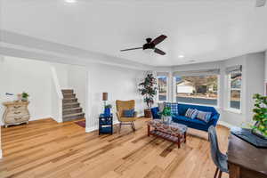 Living room with ceiling fan and light hardwood / wood-style flooring