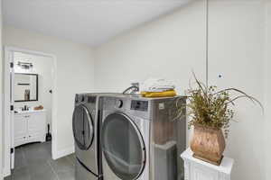 Clothes washing area with dark tile patterned flooring, sink, and washer and dryer