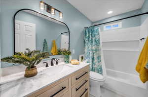 Full bathroom with vanity, shower / bath combo, and toilet