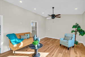 Living room with wood-type flooring, vaulted ceiling, and ceiling fan