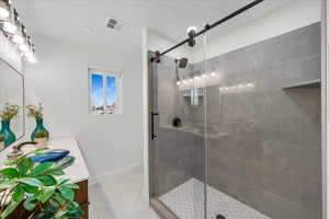 Bathroom featuring tile patterned floors, vanity, and an enclosed shower