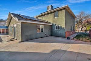 Back of house with a patio and solar panels