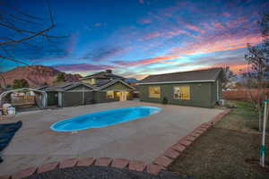 Pool at dusk with a yard, a mountain view, and a patio