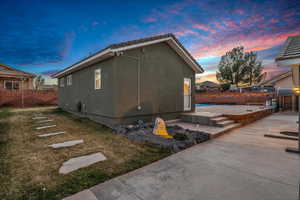 Property exterior at dusk with a patio area and a lawn