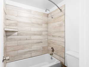 Bathroom with toilet and tiled shower / bath combo