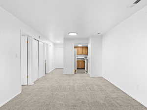 Unfurnished living room featuring light carpet