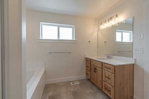 Full bathroom featuring vanity, baseboards, a tub to relax in, and visible vents