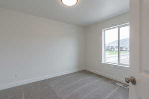 Carpeted spare room with visible vents, baseboards, a mountain view, and a healthy amount of sunlight