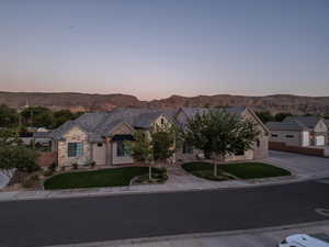 View of front of property with a mountain view and a lawn