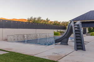 View of swimming pool featuring a water slide, a mountain view, and a patio area