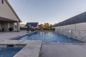 View of swimming pool with a water slide, a grill, and a patio area