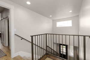 Staircase featuring wood-type flooring, a barn door, and a textured ceiling