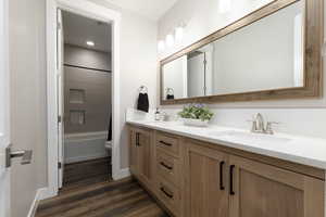 Full bathroom with vanity, hardwood / wood-style floors, tiled shower / bath combo, and toilet