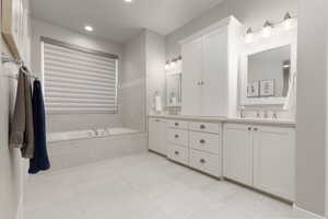 Bathroom with a relaxing tiled tub, vanity, and tile patterned floors