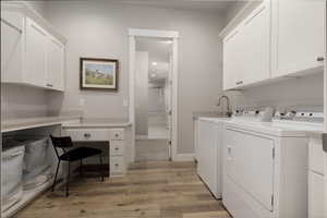 Laundry area featuring separate washer and dryer, cabinets, and light wood-type flooring