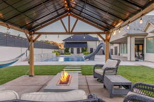 View of patio with a fenced in pool, a gazebo, pool water feature, and a fire pit