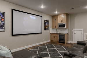 Cinema with wine cooler, a textured ceiling, dark hardwood / wood-style flooring, and indoor wet bar