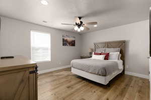 Bedroom with ceiling fan, a textured ceiling, and light hardwood / wood-style flooring