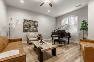 Living room with light hardwood / wood-style floors and ceiling fan