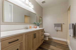 Bathroom featuring tasteful backsplash, wood-type flooring, toilet, and vanity