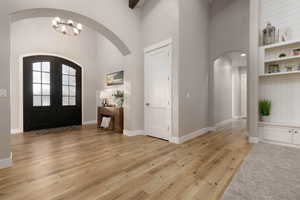 Entrance foyer with a high ceiling, a notable chandelier, light hardwood / wood-style floors, and french doors